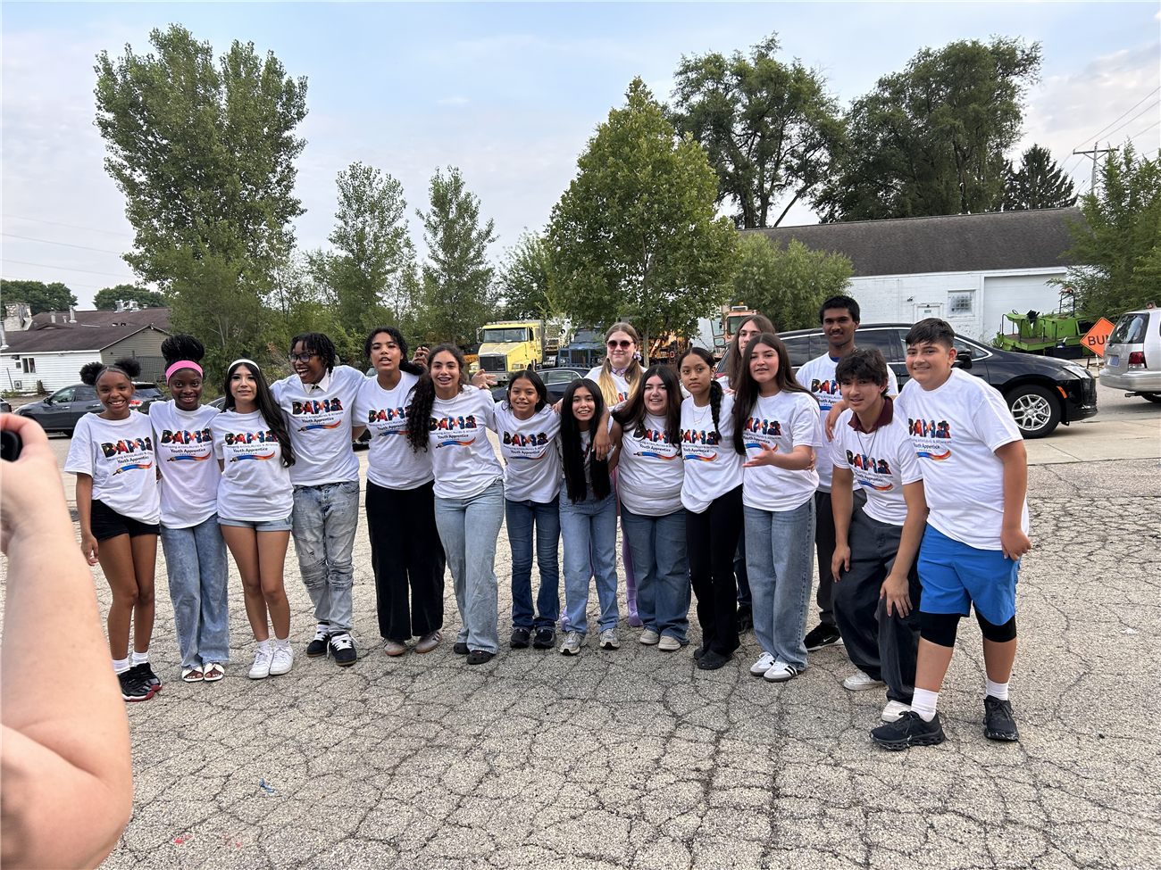 The youth apprentice cohort outside DAMA headquarters, arms around each other in matching DAMA Youth Apprentice shirts.