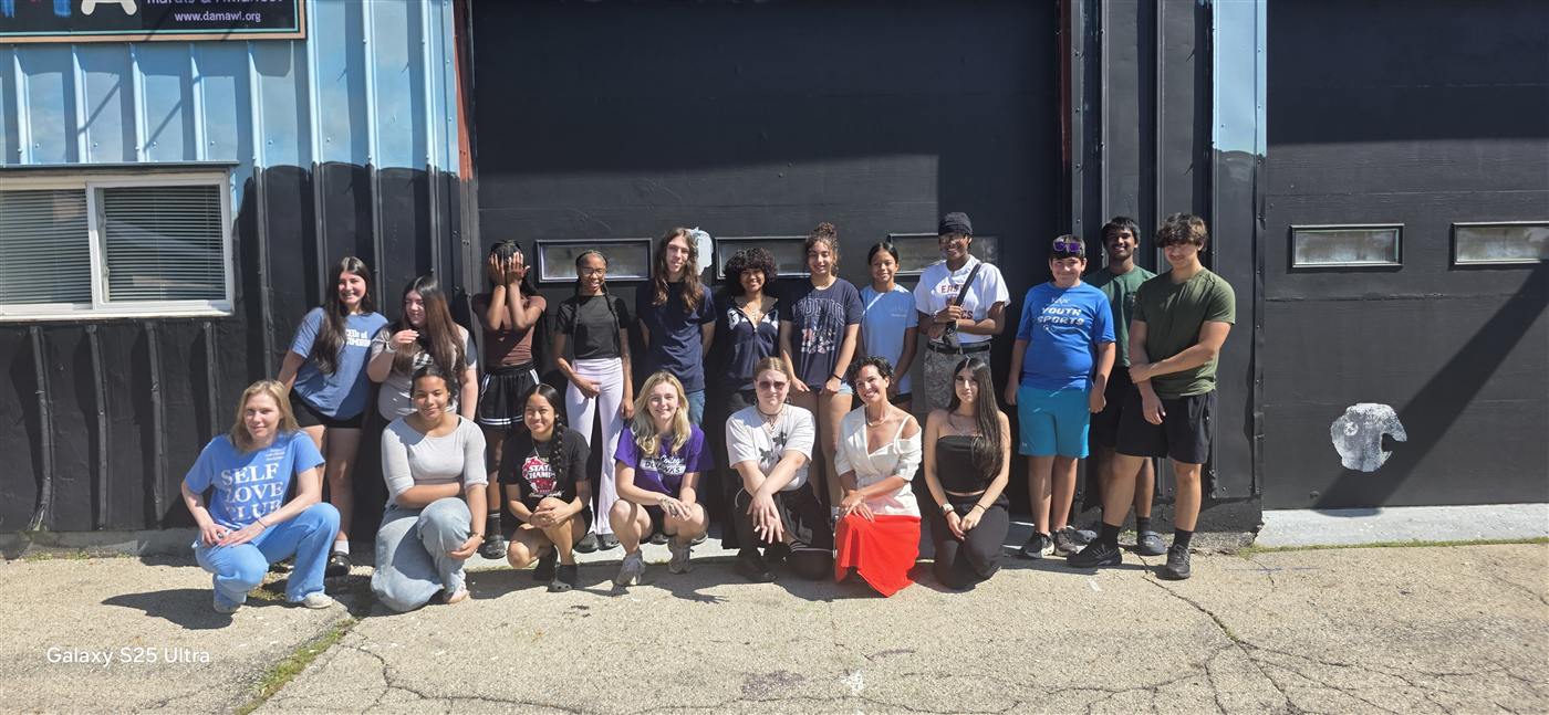 The project team outside DAMA headquarters, standing and kneeling in two rows against the building.