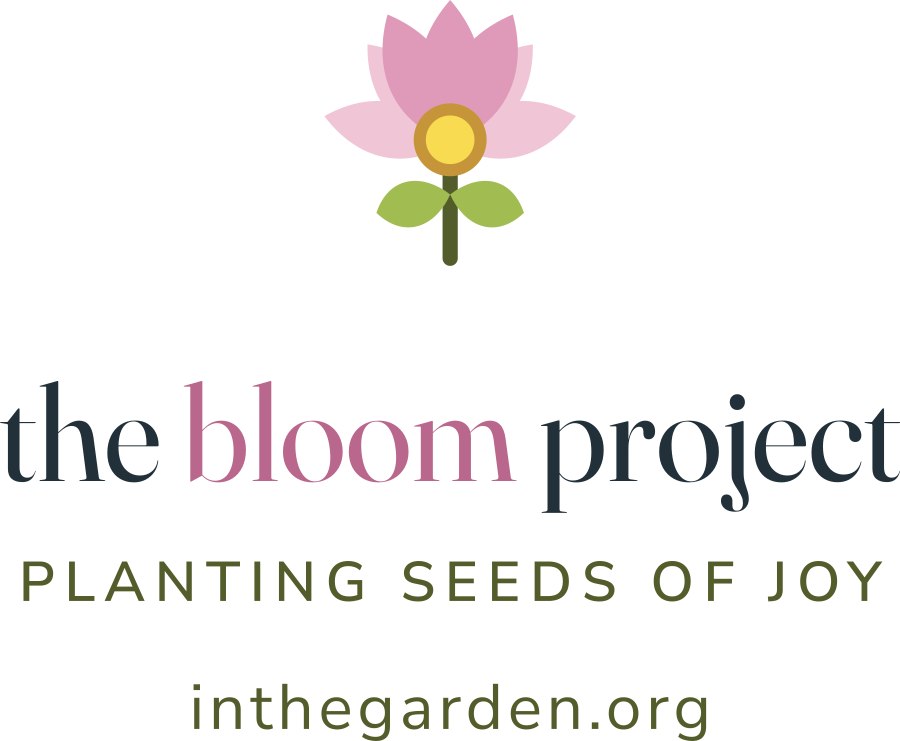 The t-shirt front print: the Bloom lotus mark above the words the bloom project, planting seeds of joy, inthegarden.org.